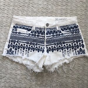 White denim shorts with blue stitching on front